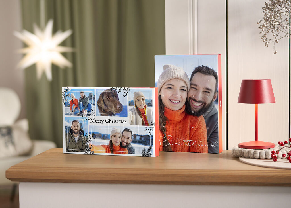 Deux CEWE albums photo festifs sur une table, l'un avec un motif de Noël joyeux.